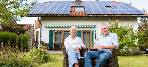 Spokojený starší pár sedíci na záhrade si užíva spolehlivou fotovoltaickou elektrárnu rodinného domu.