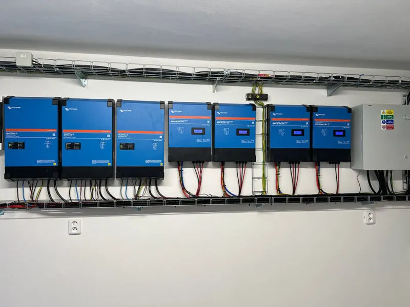 Střídače Victron MultiPlus-II a MPPT regulátory instalované na zeď v technické místnosti